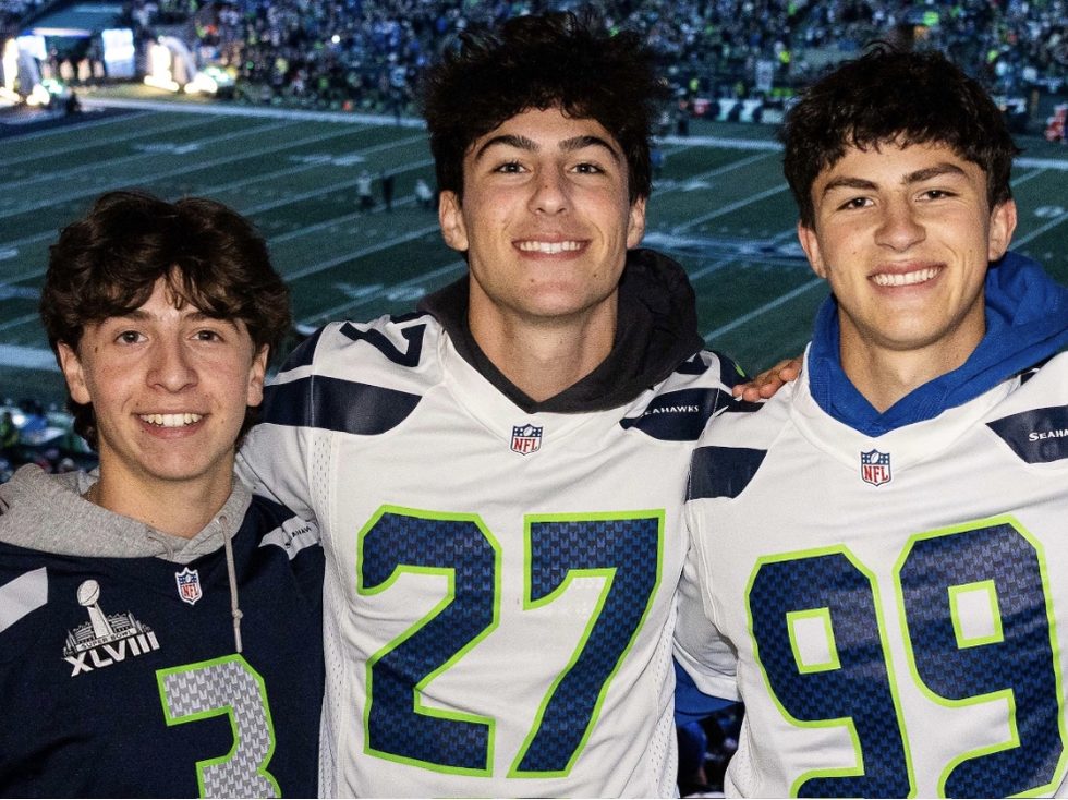 Eliot Abramson with two friends in jerseys at a football game.