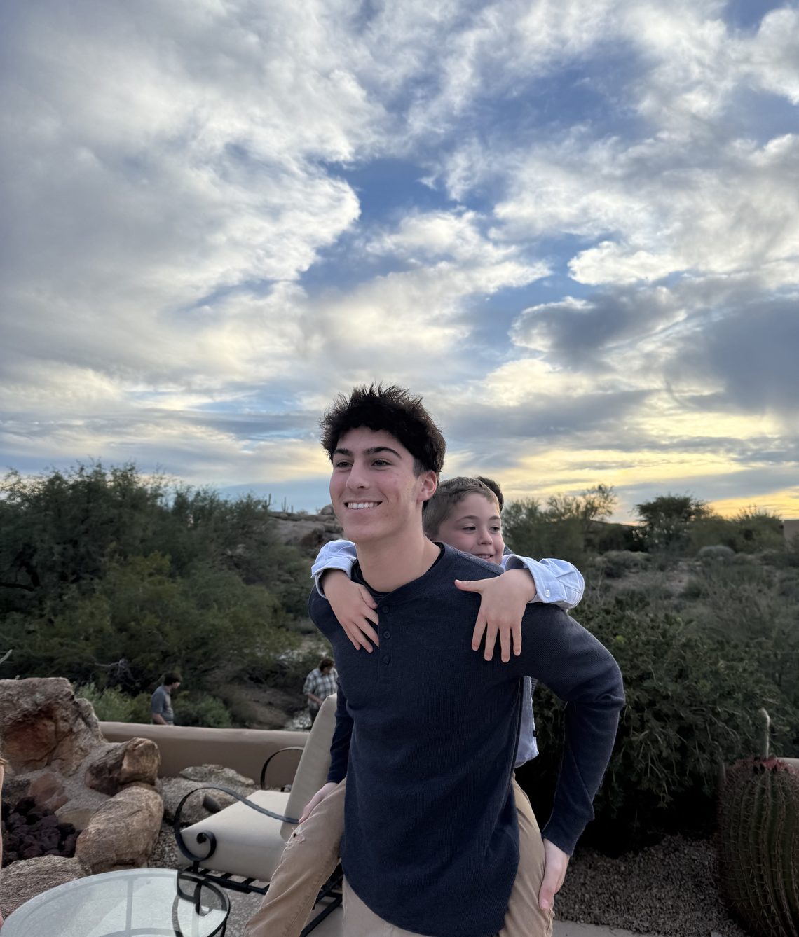 Eliot Abramson giving a younger child a piggyback ride at sunset.