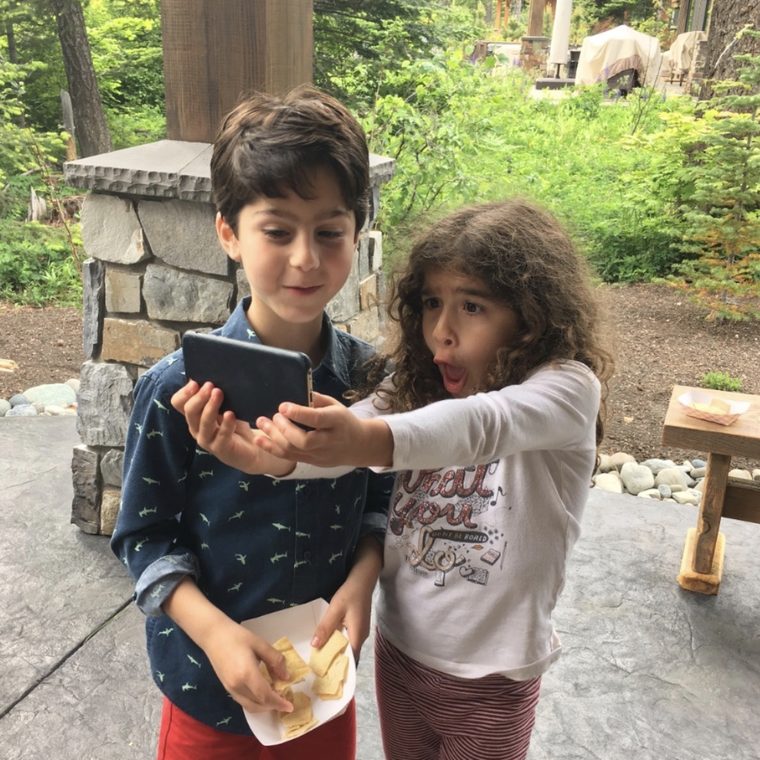 Eliot Abramson as a boy, holding a phone up with a younger child beside him.